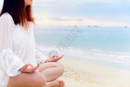 亚洲年轻女在海边的滩上做瑜伽日出时阳光照耀在大自然中放松健康与幸福和安宁对在沙滩上做瑜伽的背景亚洲年轻女来说是空白的笑声泰国水年图片