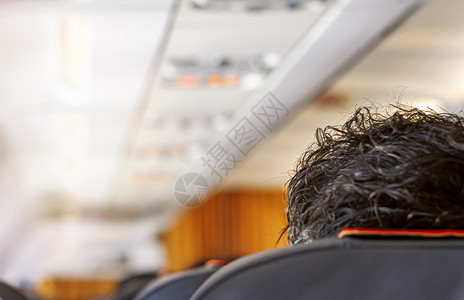 飞机头发素材排坐着现代的一架飞机内走廊飞机头顶有黑发厚的乘客口旅行和交通方式的概念旅行和运输方式概念背景