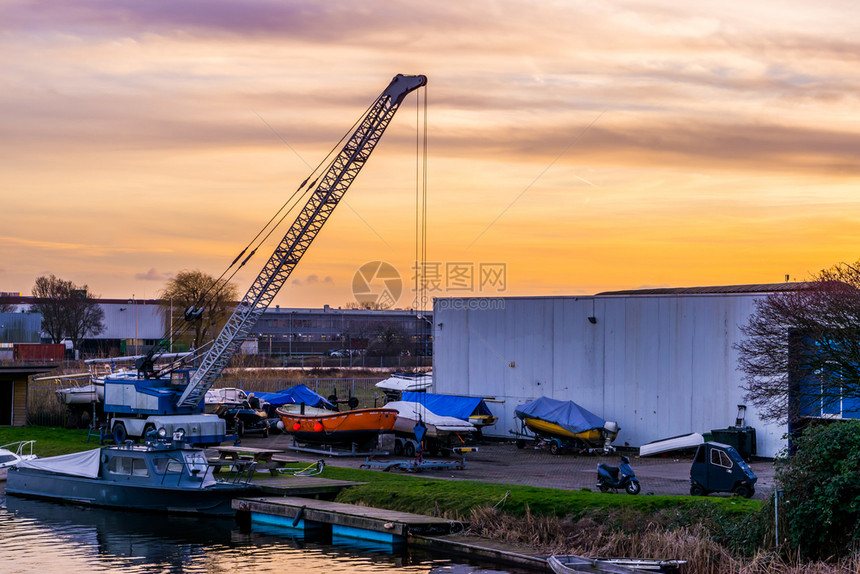 瑞金场景荷兰AlphenandenRijn港日落时有水和船只的工业区日出图片