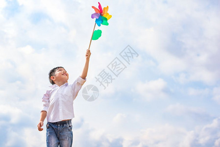 男孩在户外风中抓着多彩的针轮儿童肖像和孩子们玩主题具快乐的人们图片