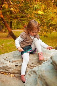 童年3的小女孩晚上在秋季公园绑鞋带叶子孩图片