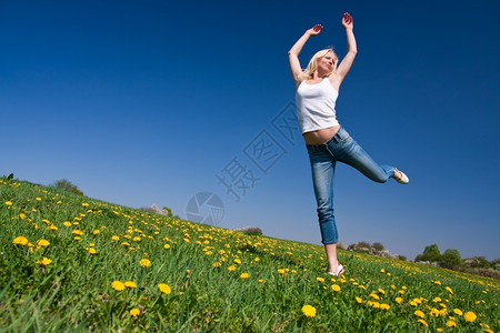 杂技演员年轻女子在花朵茂盛的草原上玩得开心成人牛仔裤图片