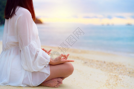 中间亚洲年轻女在海边的滩上做瑜伽日出时阳光照耀在大自然中放松健康与幸福和安宁对在沙滩上做瑜伽的背景亚洲年轻女来说是空白的笑声女孩图片