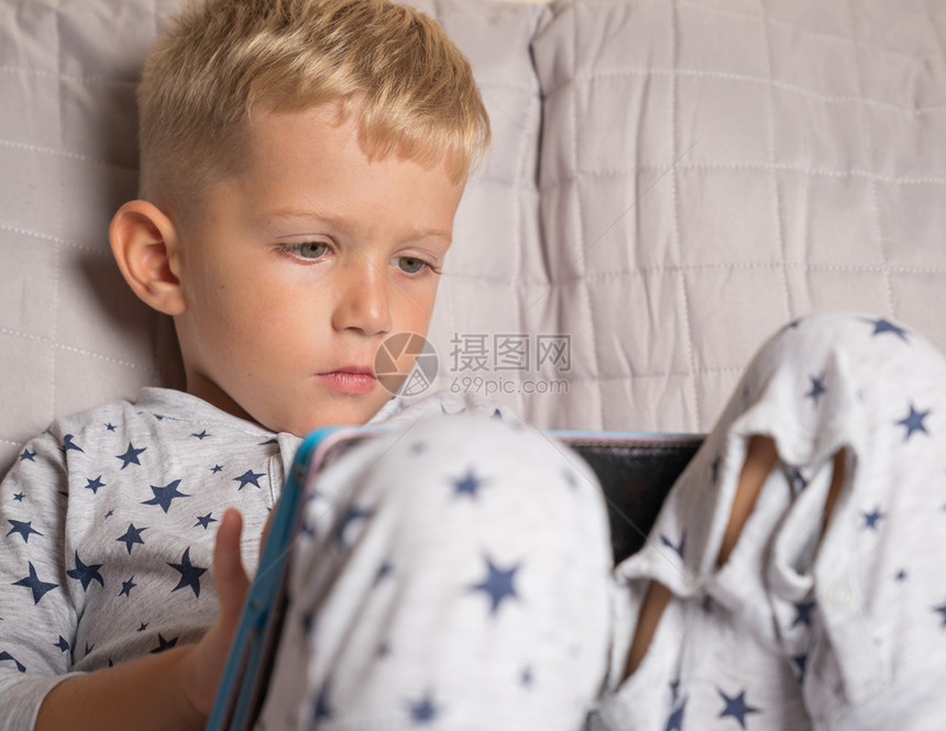 白种男孩在家中躺床上时使用数字片子的地面在室内图片