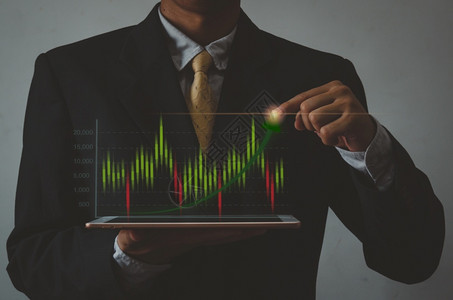 箭牌卫浴持有手平板牌和图示表股票市场的商人虚拟屏视投资业务和概念金融利润数字的男人设计图片