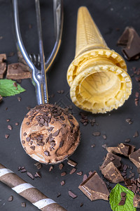 碗巧克力冰淇淋加鲜果棒甜圈和巧克力在黑板上专心吃冰淇淋舀奶油的图片