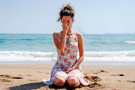 外部坐着在沙滩上穿暑期服装的年轻女子每天练习瑜伽呼吸锻炼生活图片