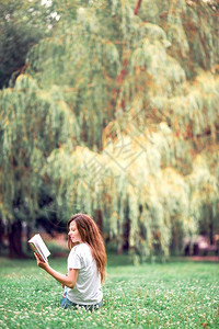 美丽的女孩在公园户外看书的年轻美少女放松了年轻读书的松度闲暇图片
