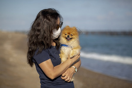 年轻女子和她的狗在海滩上晒日光浴幸福松弛可爱的图片