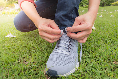 赛跑者运动员坐在花园和日落时间的鞋绳上坐到田里的鞋绳上锻炼身体图片