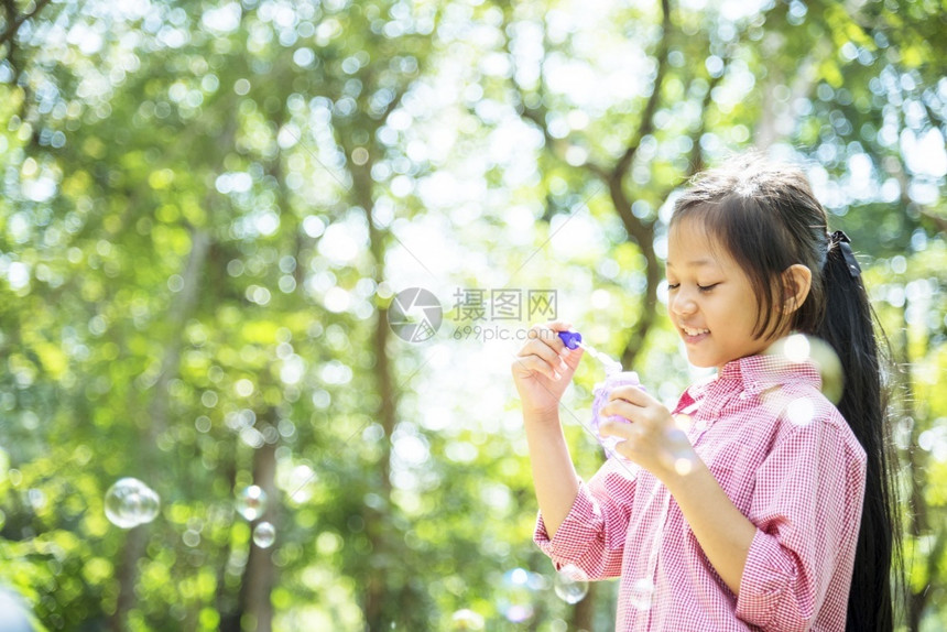 快乐可爱的女孩在夏季户外绿色游乐场玩耍泡沫在公园快乐时光中欢笑愉快的女孩在自然公园吹肥皂的泡积极美丽卷曲图片
