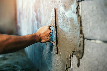 工具行业石匠人们在建筑房屋墙上涂水泥的紧手背景图片