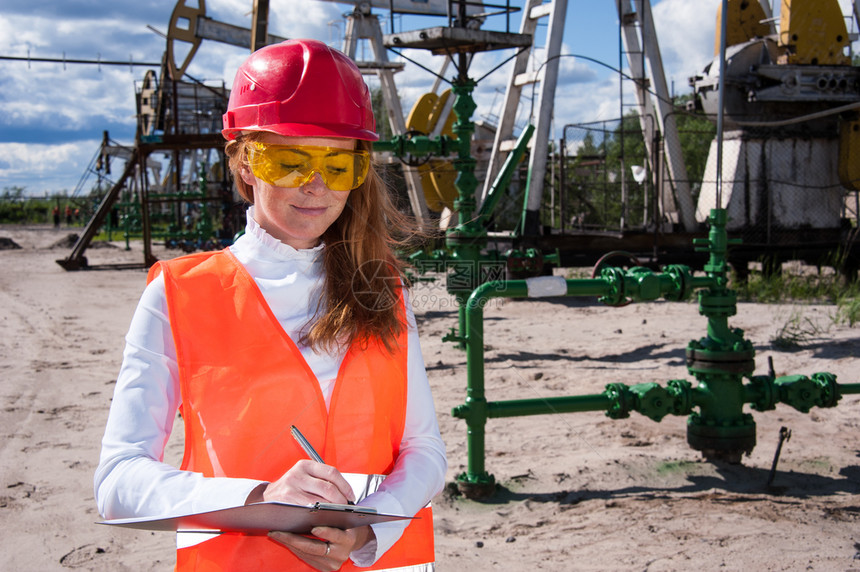 化石燃料穿戴红色头盔和工作服在油田上戴黄色眼镜的女工程师身着红头盔和工作服黄色的图片