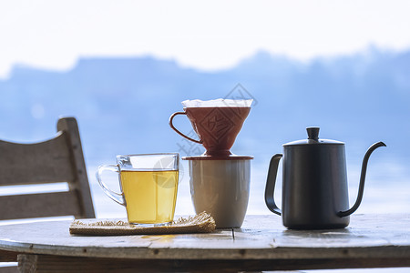 杯子滴水素材松弛一杯热芳香茶在木制圆桌上配有滴水咖啡杯与清晨的河边风景背对比水平的黑色背景