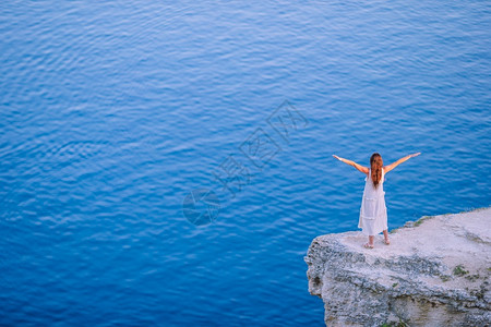 假期在悬崖边缘的快乐女人看见海景观光女游客在悬崖海岸边缘露天太阳自由图片