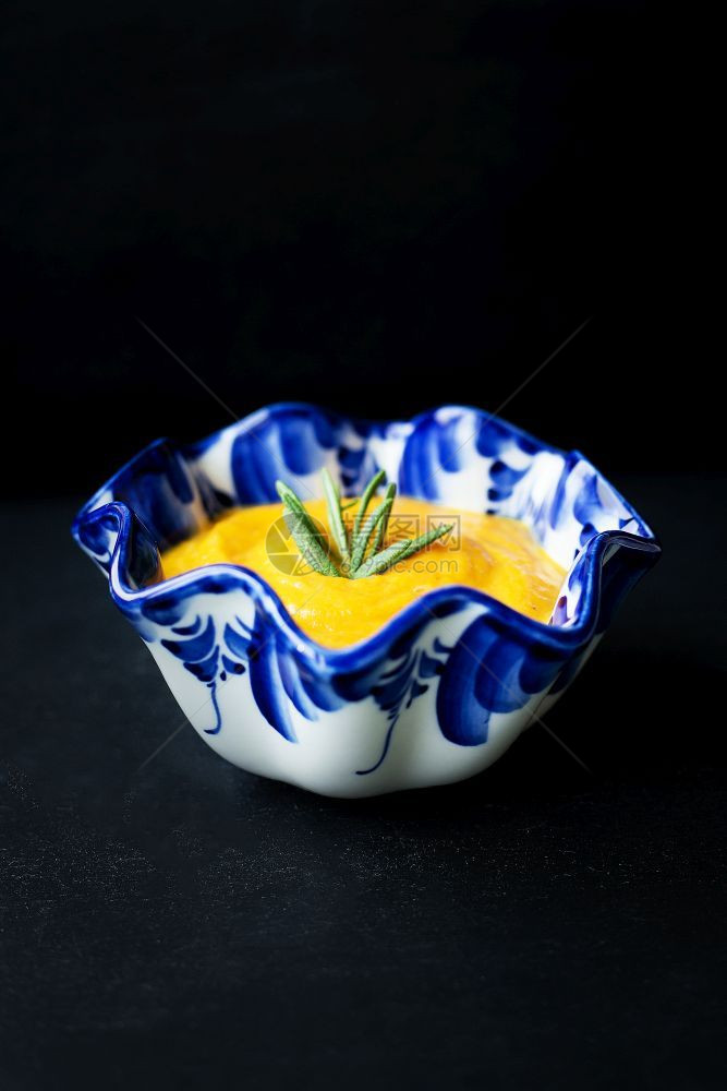 杂烩橙碗黑色背景上的蓝盘子里南瓜汤盘子里的南瓜汤图片