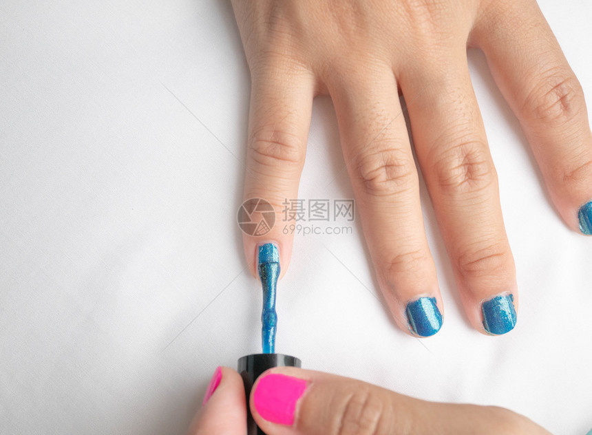 时尚髦的近身女手画蓝色指甲清漆在家里自制修指甲白色的图片