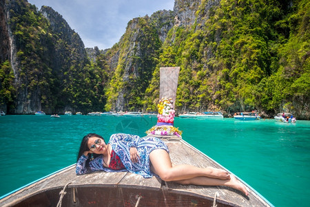 木船上女孩在泰国普吉岛菲济MayaBayPhiPhi岛马雅湾的长尾船上快乐的巴蓝色背景