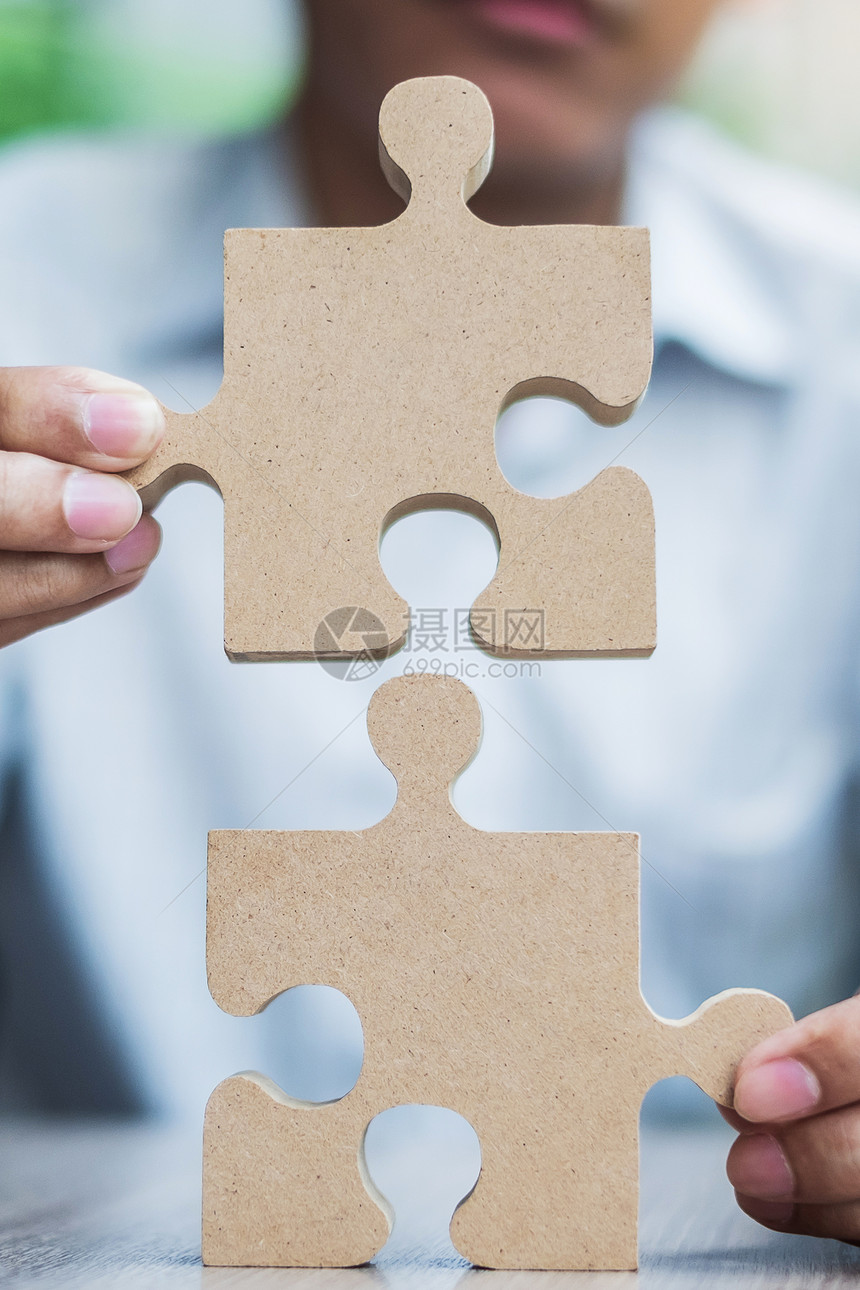 男人手在桌子上连接情侣拼图商人在办公室里拿着木拼图商业解决方案使命目标成功和战略概念不完整工作首脑图片