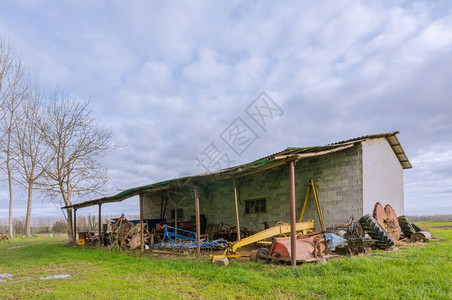 乡村失修农用工具老旧的住所背景有树木庇护所图片