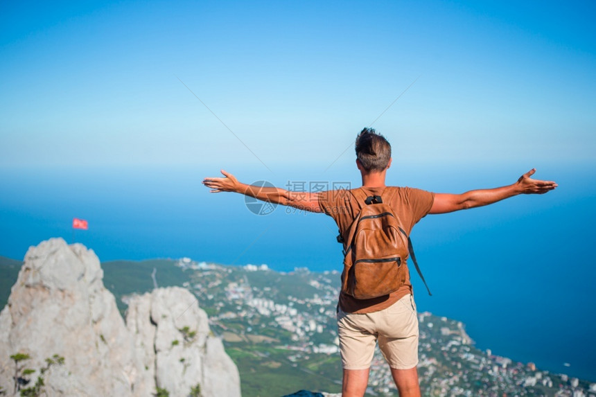 在悬崖边缘的快乐户外男人享受在山顶岩石上风景的欢快旅游者男子在悬崖海岸边缘风景最佳人们年轻的图片