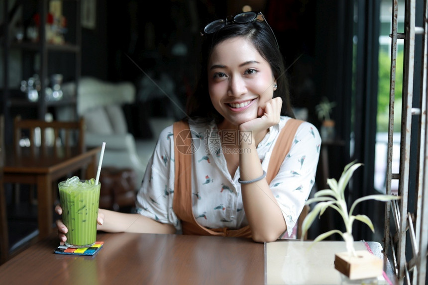 亚洲妇女微笑和快乐放松在咖啡店里喝着茶杯一种休息坐着图片