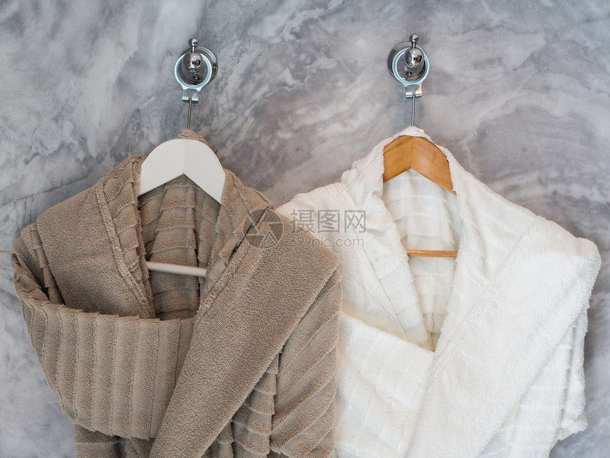 烧伤干净的挂在衣架上白色和棕清洁浴袍新的图片