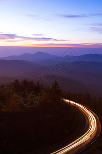 安宁户外森林黎明时的美丽山路天亮时美丽的山路有光向日出月空的卷曲山路背景运动设计图片