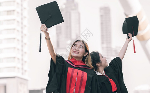 学校两名身着制服帽子和毕业后快乐笑的亚裔女学生教育概念户外年轻的学士高清图片素材