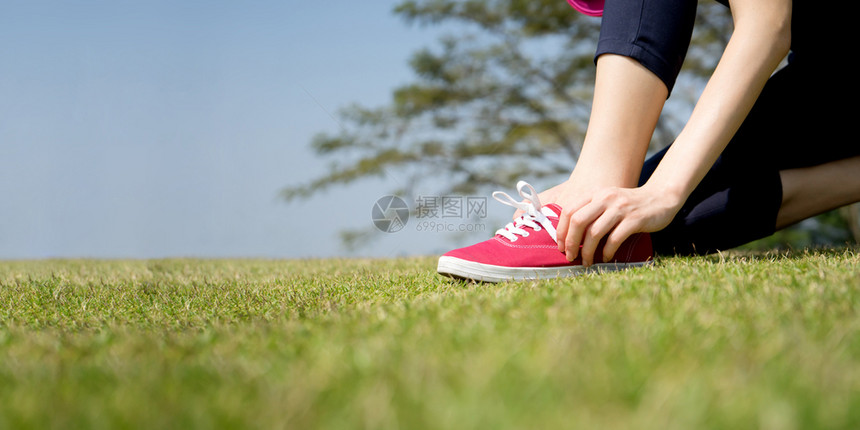 女孩脚丫子在职的跑鞋将妇女紧贴在赤脚跑鞋上系带的妇女关上运动员准备到户外慢跑图片