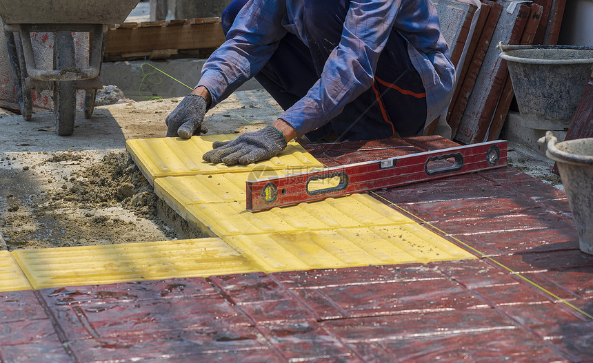 手套建筑工人有选择地把重点放在具有工作的建筑人身上即安装混凝土砖地板并铺在公共场所的步行道上改进职业图片