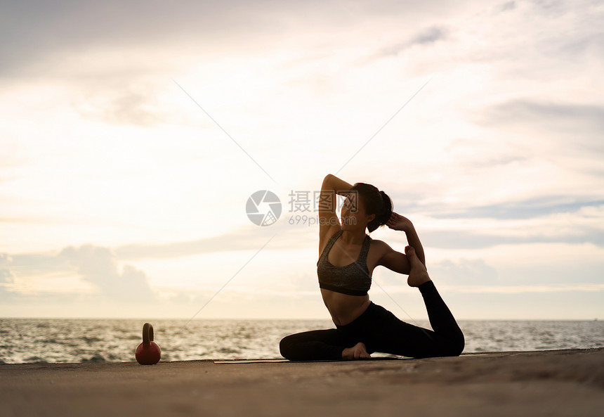 正在做合身体式超现实日落的海边健康概念和锻炼中在超现实日落期间从事瑜伽的妇女图片