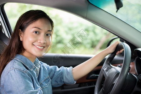 美丽的亚洲女在路上驾车旅行时微笑和愉快地开车座位一种里面图片