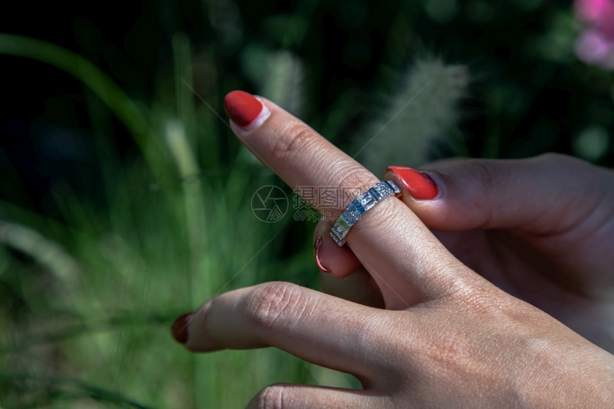 魅力四射女手妇将银戒指戴在一位士的手指上自然背景的红钉子美丽和配件选择焦点首饰珠宝图片