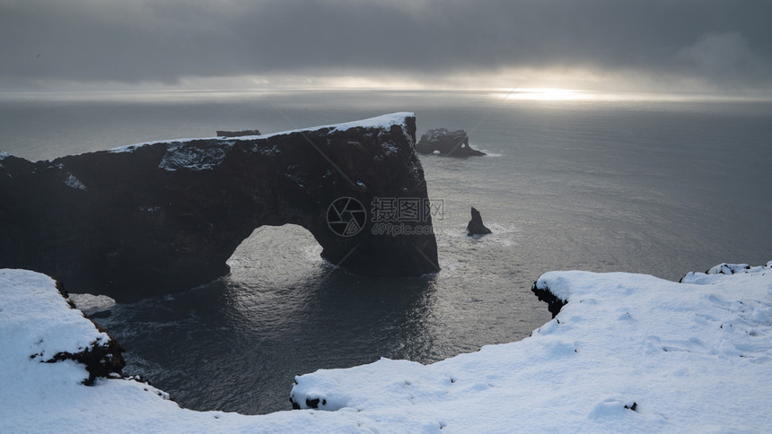冬天冰岛Dyrholaey角海岸景观的全图象在冬季与积雪覆盖海岸线的冰岛滩白雪皑图片