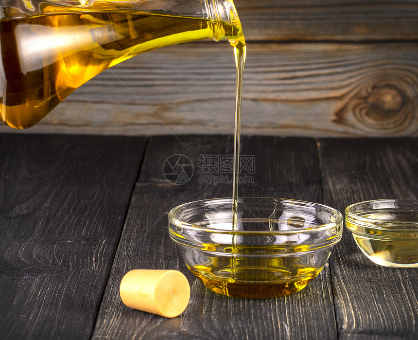 将食用油倒在旧木桌上的小玻璃杯将食用油倒在旧木桌上的小玻璃杯金透明杏仁图片