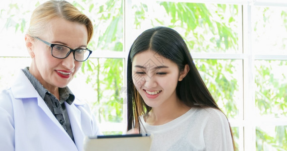 治疗医生使用数字平板电脑向女病人解释药物并到家里看病的医生护理恢复图片