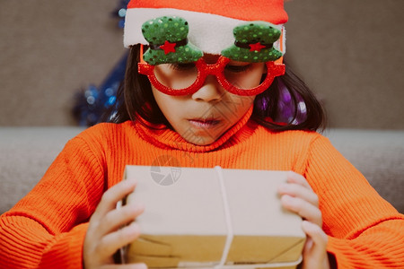 快乐的小女孩戴着圣诞帽在家带礼盒新年快乐圣诞女老人学前班图片