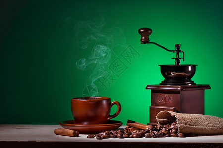 液体绿色背景中带有蒸汽咖啡研磨机和豆的带有蒸汽研磨机和豆的摩卡布奇诺图片