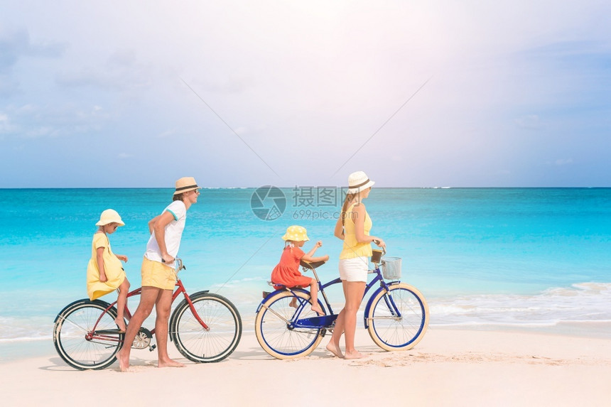 户外在海滩上骑自行车的四口之家在热带海滩上骑自行车的家庭白种人孩子图片
