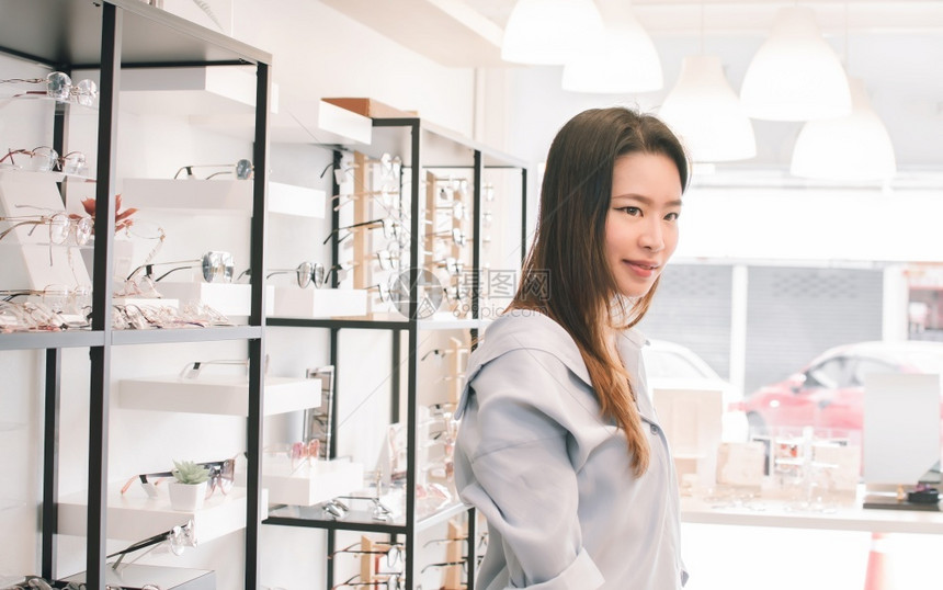 眼力亚洲美丽的年轻女子在商店销售折扣和光学概念中购物和试戴眼镜亚洲美丽的青年女子人验光师图片