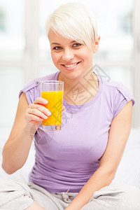 微笑白色的玻璃女金发子早餐喝果汁的照片图片