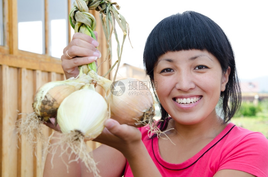 女士爆头一个年轻的亚洲女人拿着新鲜洋葱和微笑黑色的图片