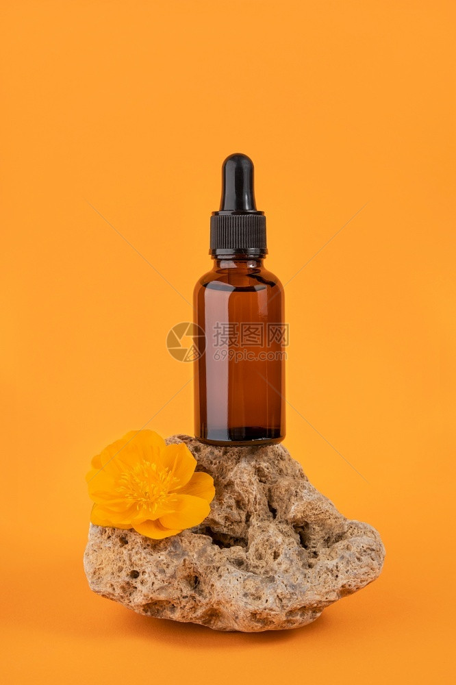 关心皮肤护理产品棕色玻璃瓶中的血清或精油吸管在石头上橙色背景的花朵天然有机Spa化妆品概念正面图棕色玻璃瓶中的血清或精油橙色背景图片