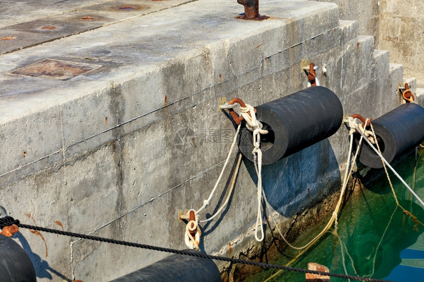 绿松石目的在古老混凝土码头上用绳索和生锈的金属括带固定在松石海蓝水和港以及翼码头附近的浮壳和机翼码头停泊力量图片