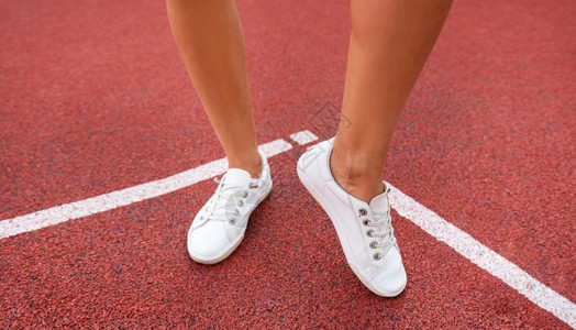 操场上的红色塑料涂层穿着白色运动鞋的女孩腿为比赛做准备景观红色的工作图片