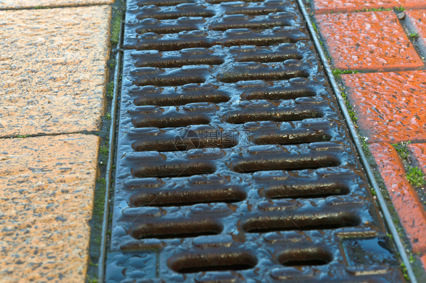 粗糙的排水沟铺红黄瓦人行道排水格栅是人行道上的雨水槽人行道排格栅是人行道上的雨水槽铺有红黄相间的瓷砖下水道覆盖图片