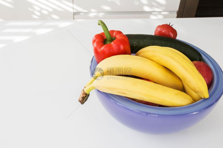白桌上紫色碗中的蔬菜和水果特写白桌上紫色碗中的蔬菜和水果吃素食主义者颜色图片