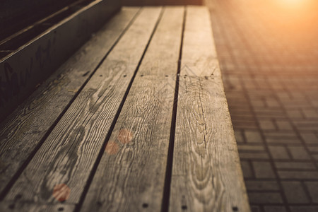 场景绿色速连科现代木制板凳深质的木制板凳在日落温暖阳光下关闭图片