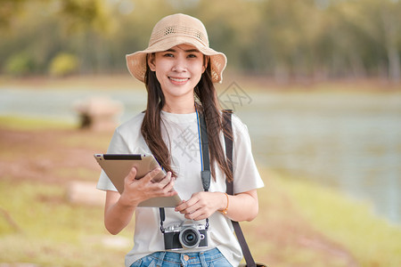 户外手拿平板电脑和相机旅游的女性图片